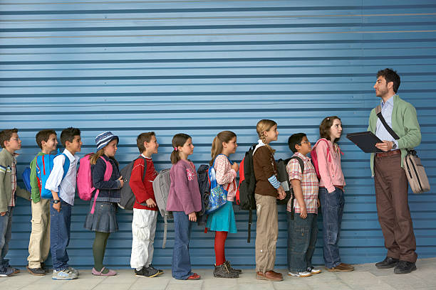 insegnante maschio, fila di bambini (8-12), vista laterale - persone in fila foto e immagini stock