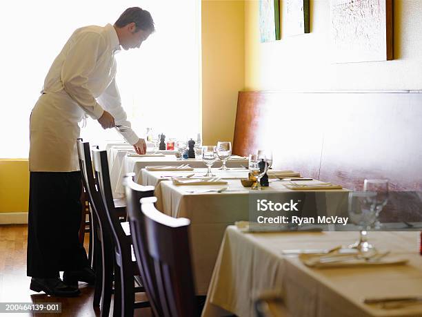 Young Man Setting Tables In Restaurant Side View Stock Photo - Download Image Now - Restaurant, Waiter, Luxury