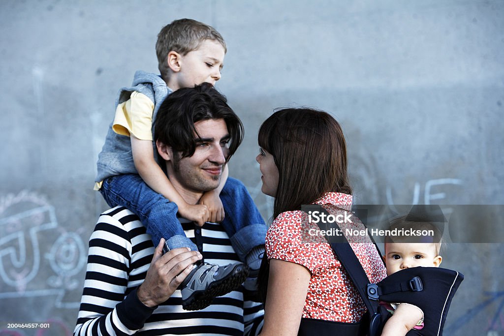 Uomo portare figlio (2-4) e donna per il trasporto di bambini (9 mesi), uscita - Foto stock royalty-free di 2-3 anni