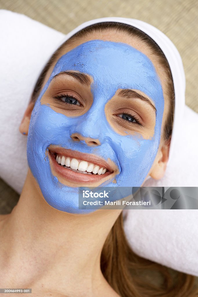 Young woman wearing facial mask, smiling, portrait, close-up  Facial Mask - Beauty Product Stock Photo