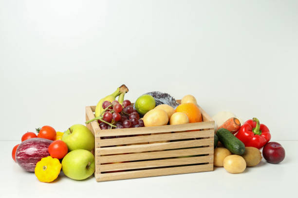istock Wooden box with different vegetables and fruits on white table 2004651762