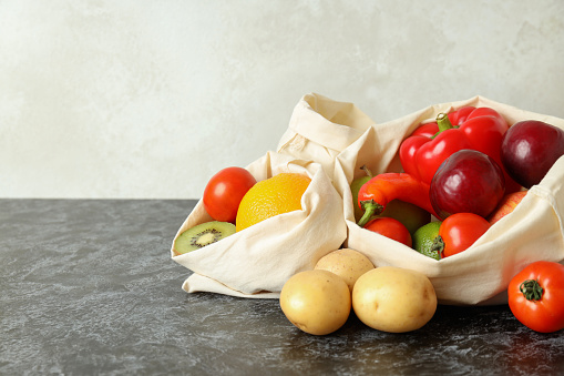 Bags with vegetables and fruits on black smokey table