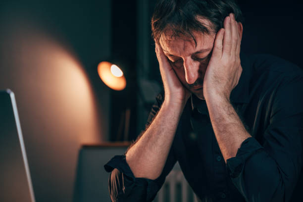 istock Headache at work, exhausted businessman sitting at office desk with severe head pain while working overtime 2004668491