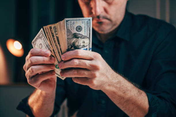 istock A well-dressed businessman counting american dollars at office desk 2004669002