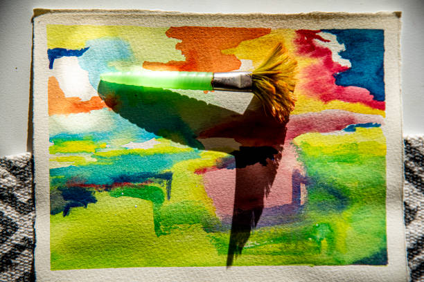 Paintbrush and paint can on abstract colorful watercolor background.