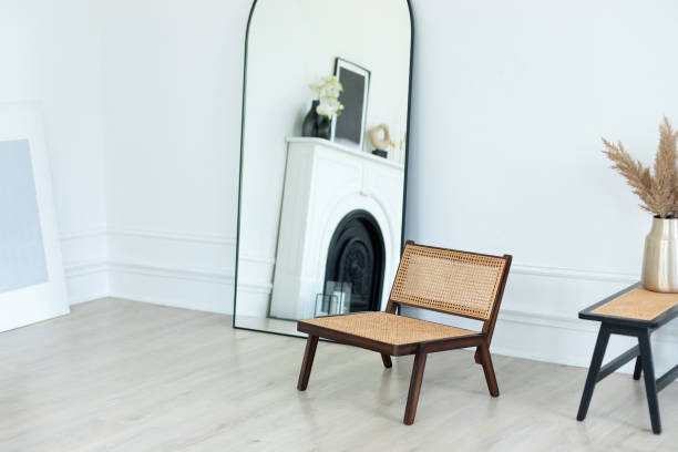 istock Stylish Skandi and minimalistic composition at living white room interior with design rattan armchair, large mirror  near wall and table with dried flowers in stylish home decor. Template. Copy space. 2004681900