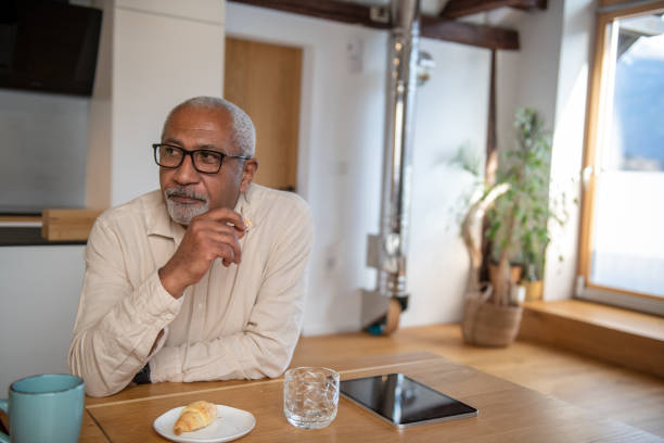 Senior man eating breakfast at home stock photo