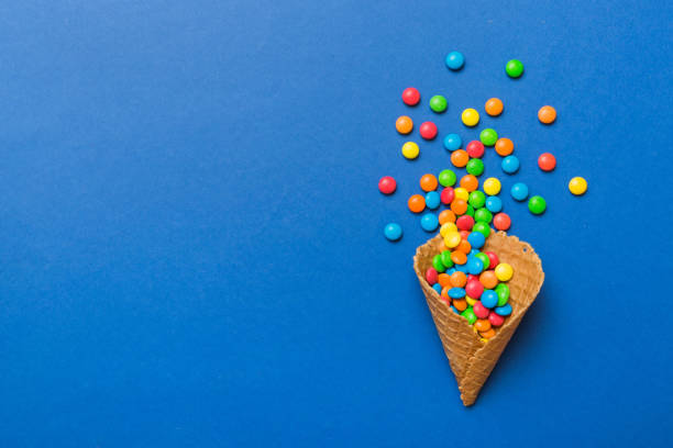 istock waffle cone full of assorted traditional candies falling out on colored background with copy space. Happy Holidays sale concept 2004685155