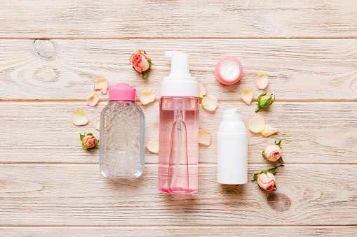 Fancy healthcare bottles for serum, micellar, tonic, toner, lotion, water and cream with rose flower. Natural oranic spa cosmetics concept. Mockup, template, Top view.