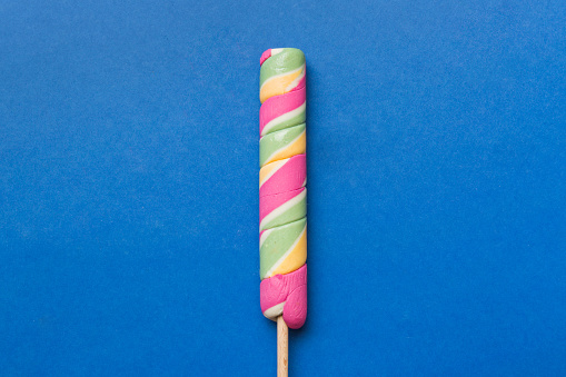 Multicolored candy or cake on a stick on a white background. A beautiful dessert.