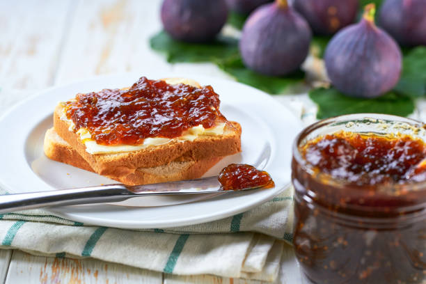 Plate with slices of bread and delicious figs jam on wooden table.