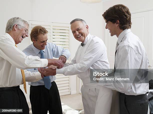 Foto de Três Homens Ajudando O Homem Sênior Com Botões De Punho Sorrindo e mais fotos de stock de 25-30 Anos