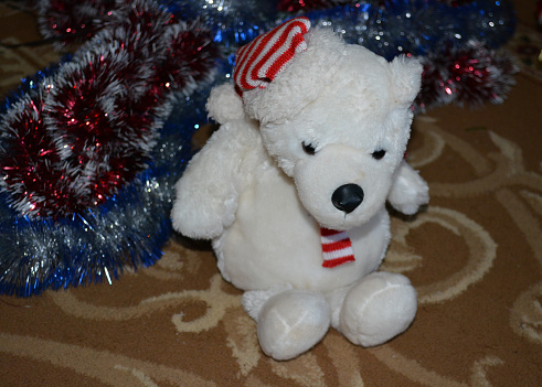 White fluffy toy bear surrounded by New Year 's Eve garlands. New Year's Toy Attributes