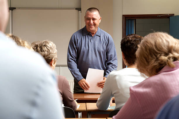 Mature men and women in classroom, teacher standing at front  nontraditional student photos stock pictures, royalty-free photos & images
