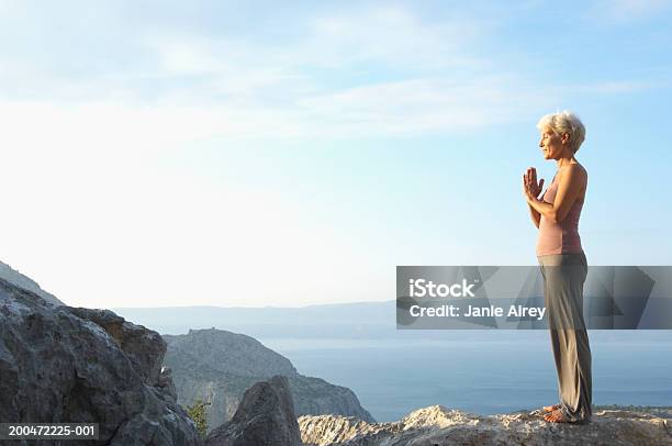 Mature Woman With Hands Pressed Together In Mountain Landscape Stock Photo - Download Image Now