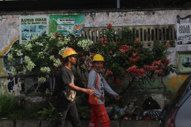 Yogyakarta, Indonesia, February 4, 2024; Portrait of two construction workers with safety helmets walking to the project site on a sunny morning.