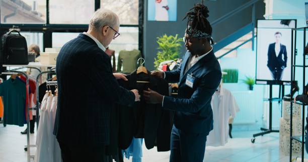 istock African american store assistant helping regular client with a suit 2004731613