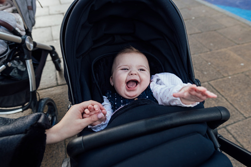 Point of view of an unrecognisable young mother checking on her baby daughter in her pram, she is looking playful and excited while her mother is holding her hand on a walk in the city in Newcastle-upon-Tyne, North East England.