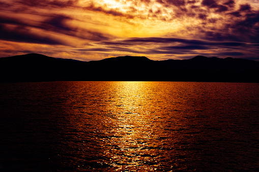 sunset over the lake with the silhouette of the mountains in the background