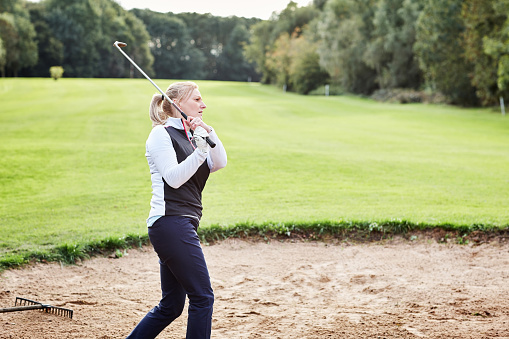 Golf, sand and woman golfer playing with ball and metal club on outdoor pitch or field. Sports, mud and female athlete hitting equipment on outside course for match, training or game practice.