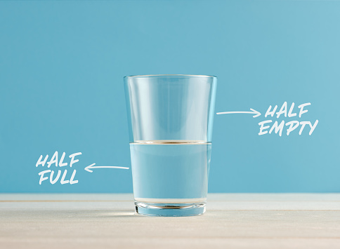 Optimism and Pessimism concept. Water glass with the words half full and half empty. Positive or negative attitudes.