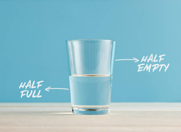 Optimism and Pessimism concept. Water glass with the words half full and half empty. Optimism and Pessimism concept. Water glass with the words half full and half empty. Positive or negative attitudes. opposite words full and empty stock pictures, royalty-free photos & images