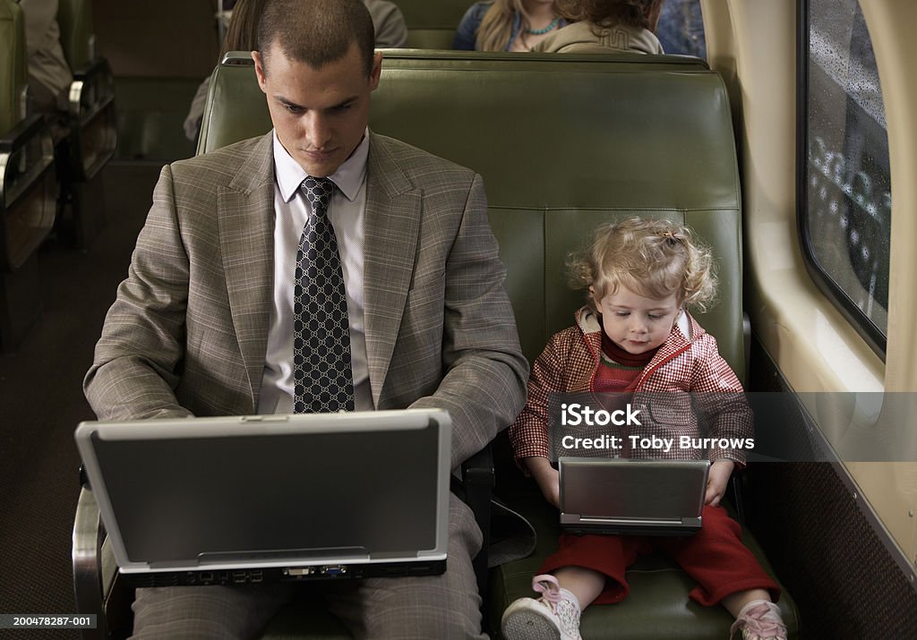 Padre e figlia sul treno (1-3) utilizzando un computer portatile e lettore DVD - Foto stock royalty-free di Treno