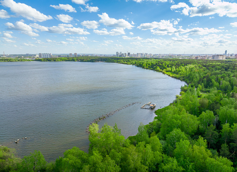 Big lake with green shores in bright sun light and city on horizon, aerial landscape. Recreation concept. Sky reflection. Ecology in Europe. Aerial view. Lake Shartash and Yekaterinburg, Russia