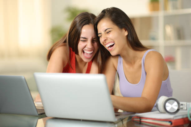 istock Happy students laughing watching media on laptop 2004784558