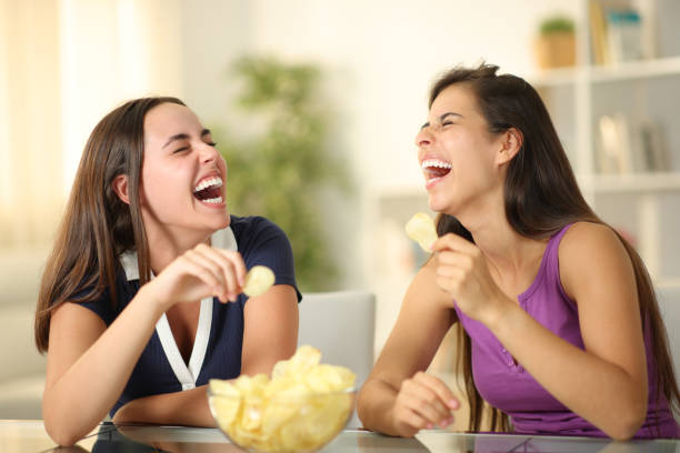 istock Happy friends laughing hilariously eating potato chips 2004786671