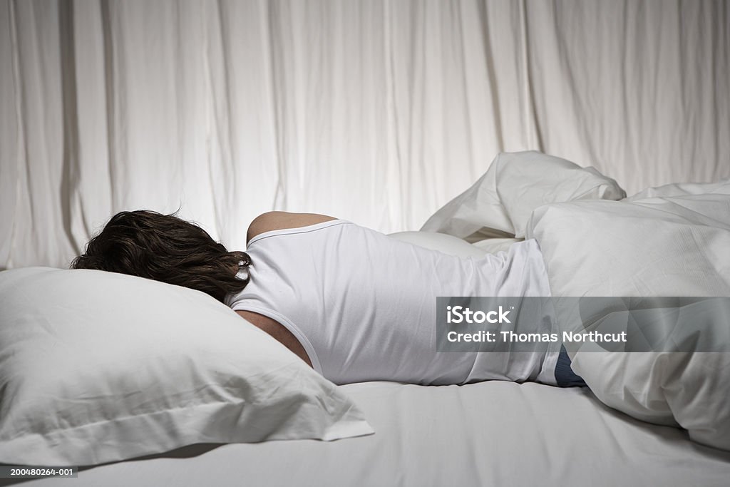 Junger Mann liegt im Bett, Ansicht von hinten - Lizenzfrei Schlafen Stock-Foto