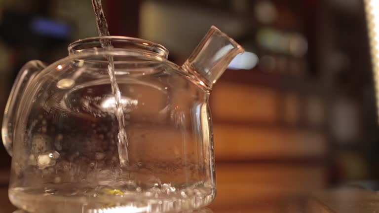 Water pours into a clear glass kettle. Clear Glass Teapot Filling with Water