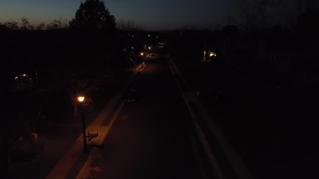 American neighborhood at night. Aerial flight on residential street with lamps and houses.