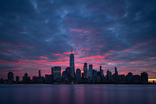 Night atmosphere with red pre-sunrise clouds above Lower Manhattan cityscape. New York panorama as captured from New Jersey.