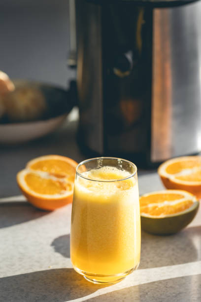 istock Fresh orange juice in a glass close up on kitchen table. 2004825814