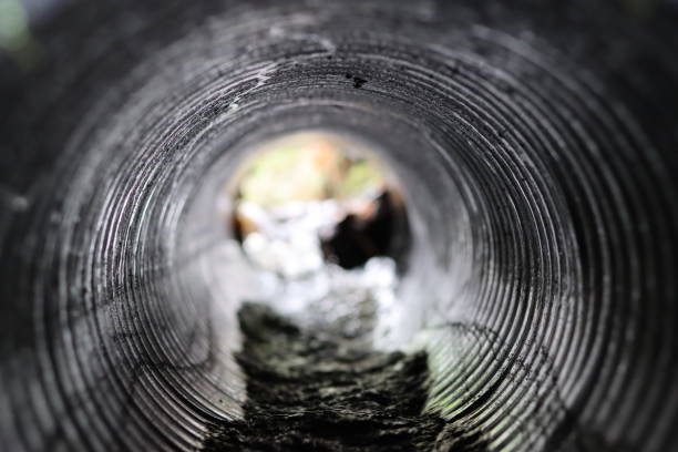 View through a round tunnel carrying a stream beneath a road
