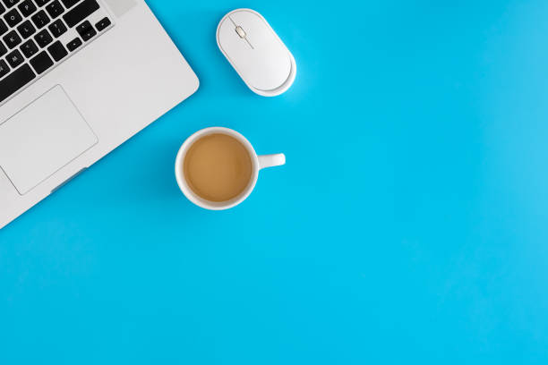 istock Cup of coffee, computer mouse and laptop on a blue background, top view. 2004833673