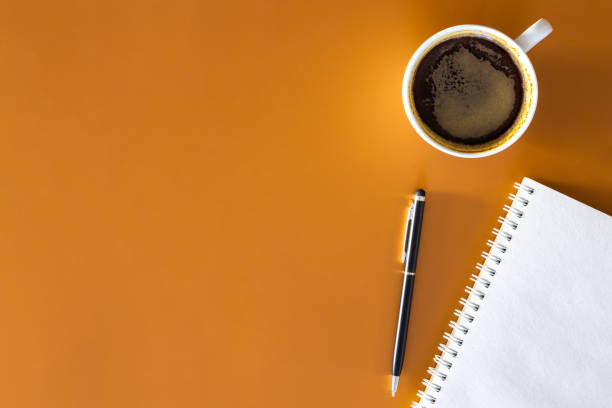istock Notepad, pen and cup of coffee on a brown background, flat lay. 2004835310