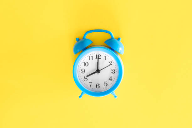 istock Blue alarm clock on a yellow background, top view. 2004835312