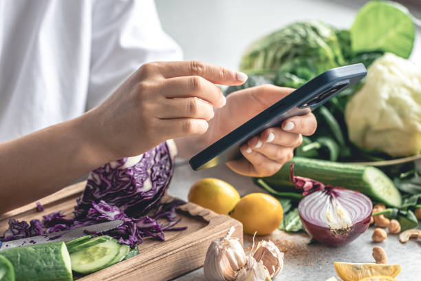 istock A woman uses a smartphone in the kitchen while preparing a vegetable salad. 2004844920