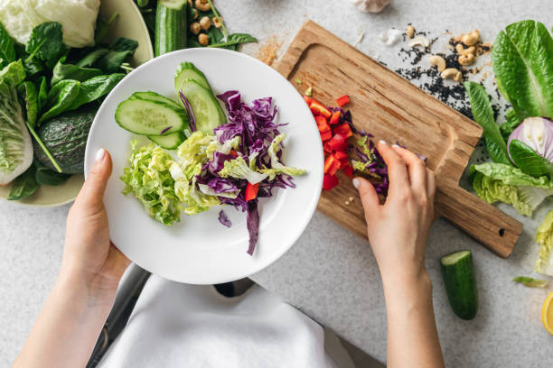 istock A plate with chopped fresh vegetables in female hands in the kitchen, top view. 2004853571