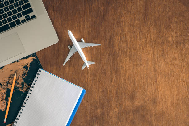 istock Airplane miniature, notepad, World map and laptop on a wooden table. 2004860124