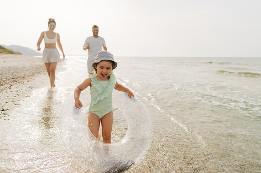 Photo of a young family with one child, who enjoy spending time on the beach