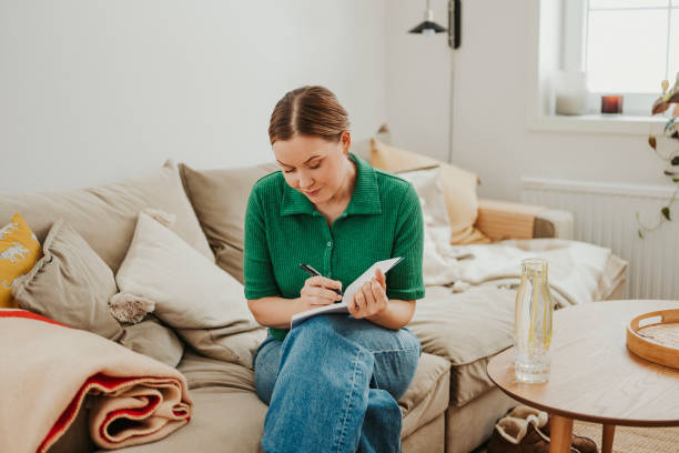 istock Woman indoors at home relaxing on sofa with her analog notebook 2004884131