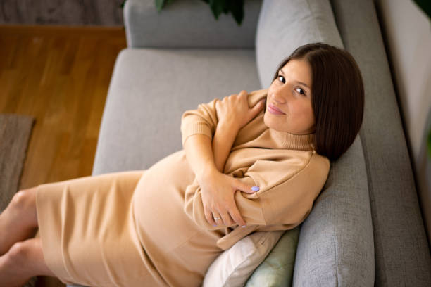 istock Pregnant woman hugging herself while sitting on the sofa 2004887284