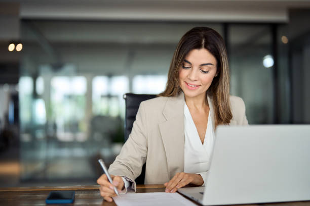 istock Busy mature business woman writing notes working on laptop in office. Copy space 2004890549