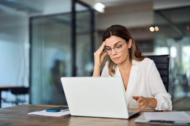 worried fatigued mature business woman wearing glasses having headache at work. - tensão imagens e fotografias de stock