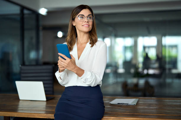 istock Smiling mid aged business woman using cell phone working in office. Copy space. 2004891068