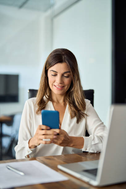 istock Happy mid aged 40s business woman using cellphone working in office. 2004891075