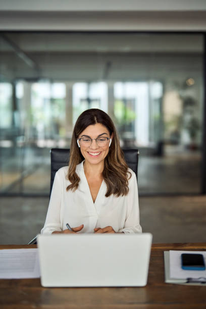 mujer de negocios madura feliz que tiene una reunión híbrida en la oficina, vertical. - interview the media marketing adult fotografías e imágenes de stock